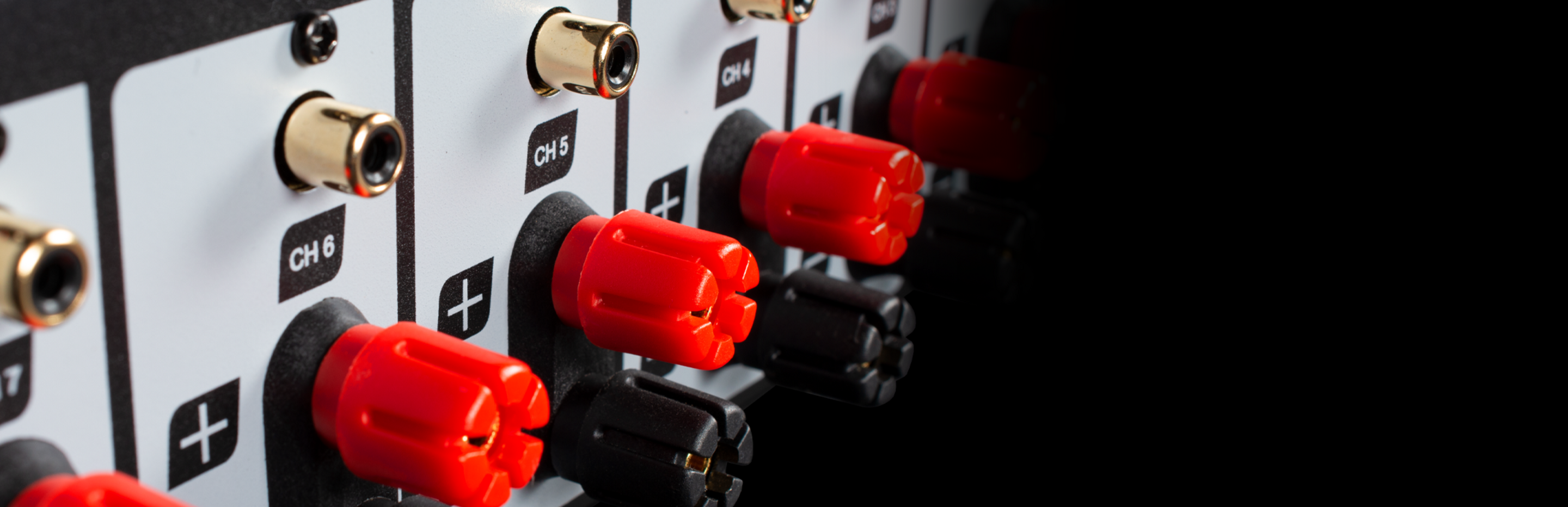 Close-up of the back panel of an amplifier with red knobs on a black background