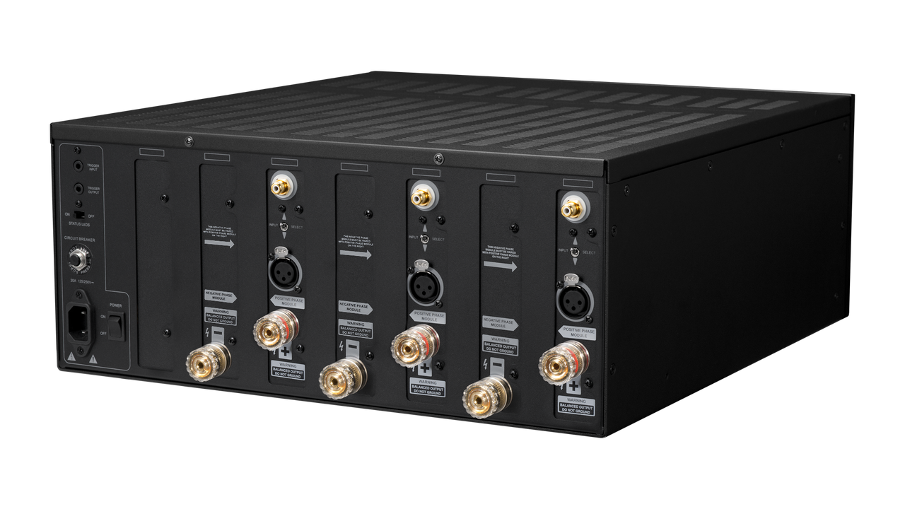 A black rectangular power amplifier shown from a three-quarters angle on a white background. The rear panel features multiple gold-plated BNC connectors, XLR inputs, power ports, and various technical labels.