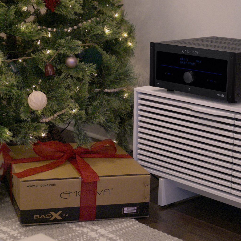 Black electronic device on a white surface with a decorated Christmas tree in the background