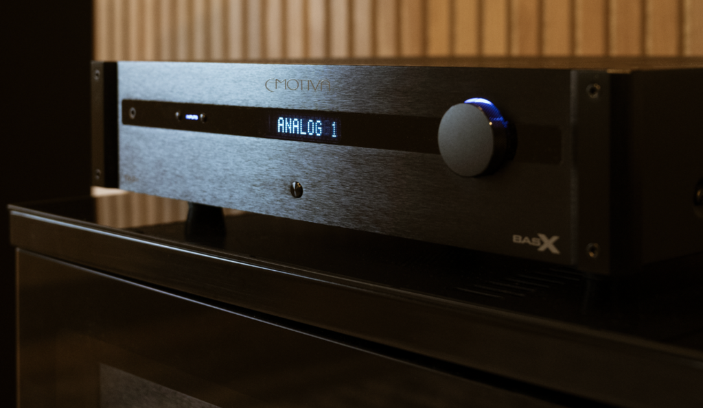 Black audio amplifier with digital display and control knob on a wooden background