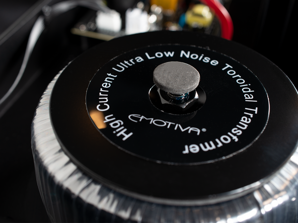 EMOTIVA high current ultra low noise toroidal transformer on a dark background