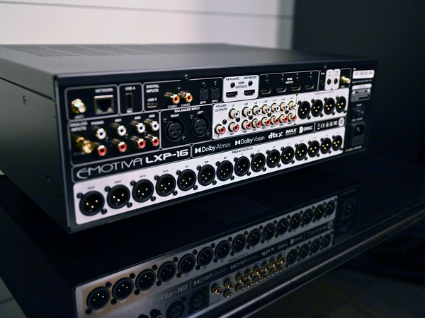 A close-up of the rear panel of a Emotiva LXP-16 audio receiver, showing multiple XLR, RCA, and digital input/output connectors on a dark surface.